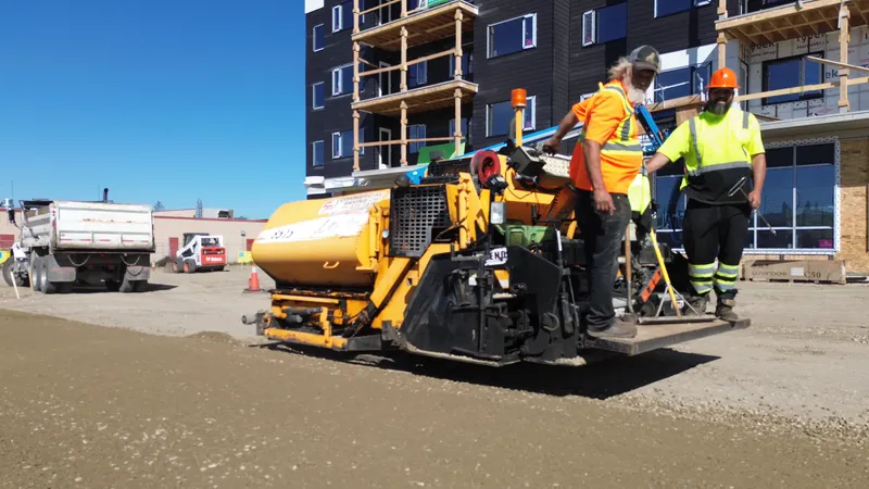 Commercial Paving crew on the LeeBoy paver during gravel base work at a Calgary-area apartment site