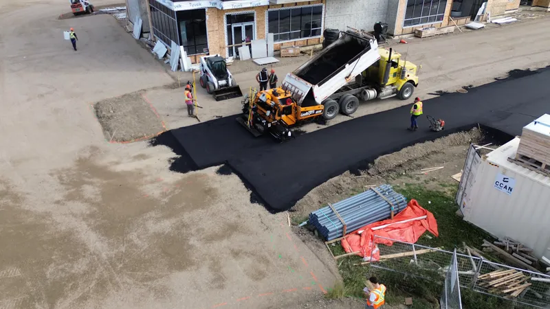 Dump truck feeding the paver as the first hot mix asphalt mat is placed on a new parking lot