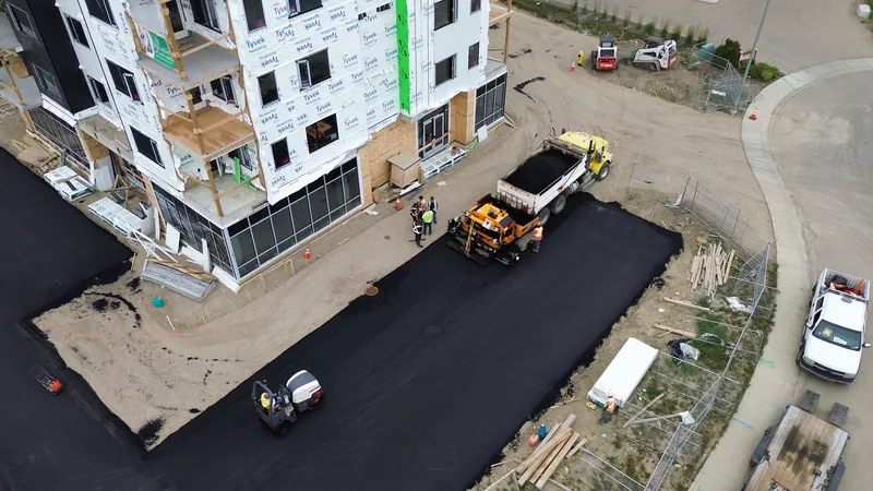 Finished asphalt parking lot from above with the paver, truck and roller still on site