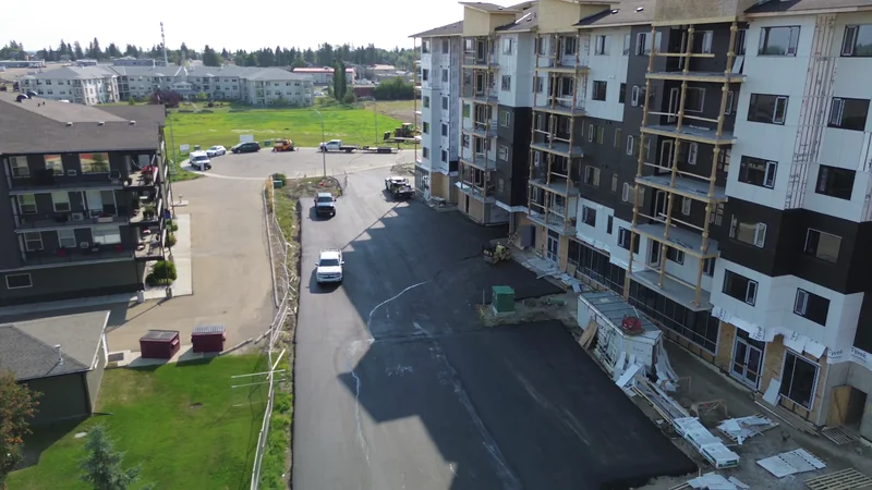 Aerial of the completed asphalt parking lot beside a new apartment building in Olds