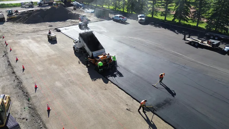 Hot mix asphalt being placed by paver and raked by Commercial Paving crew